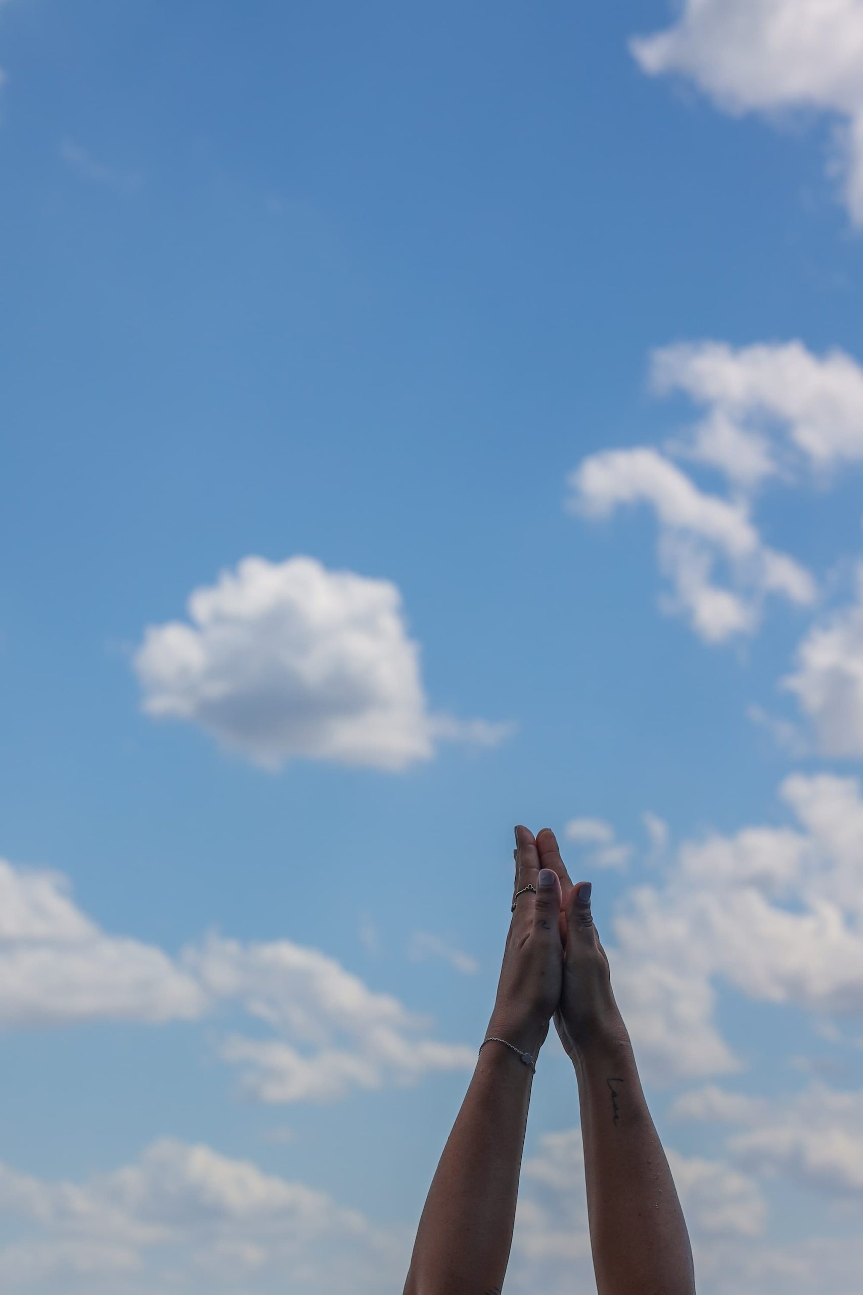 prayer yoga hands in blue sky with clouds